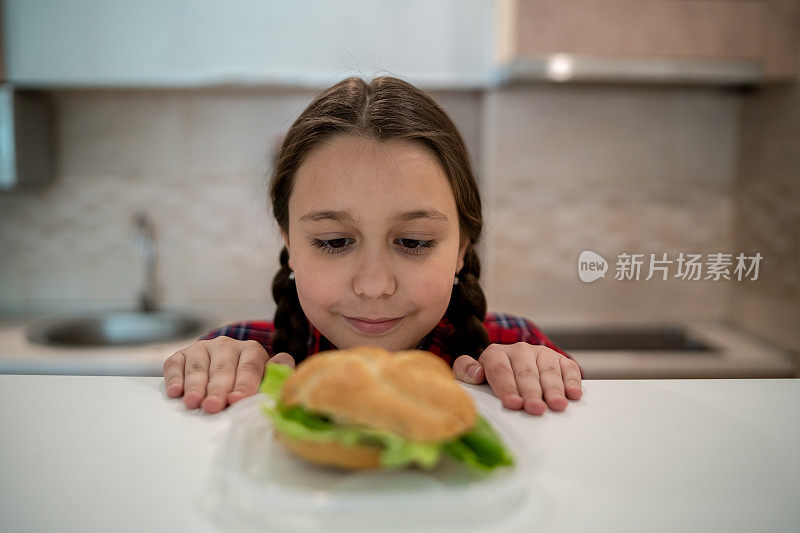 十几岁的女孩看着开胃的汉堡躺在她面前的桌子上