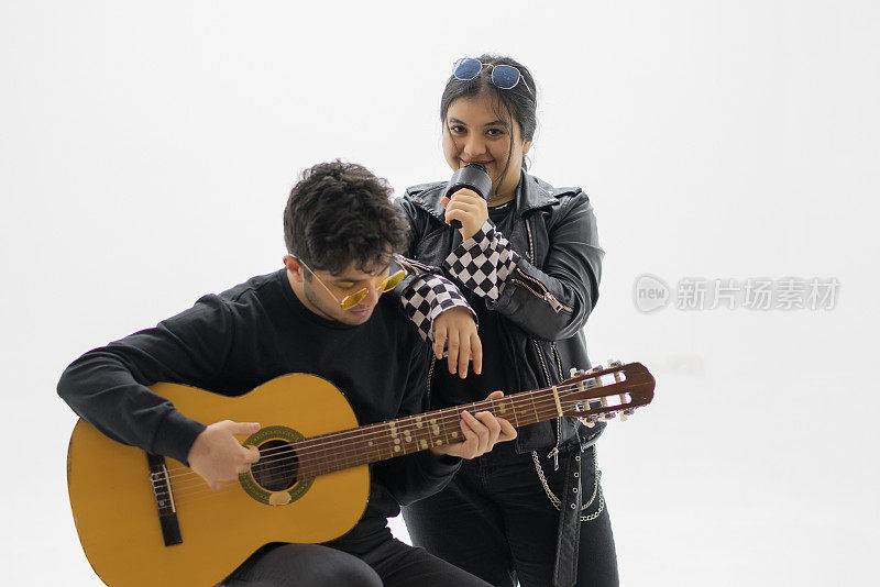 一对快乐的年轻情侣一边唱一边弹吉他。