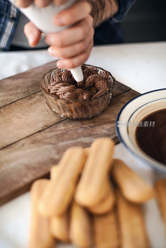 隔离烹饪:一名男子正在用糖衣袋给提拉米苏填馅