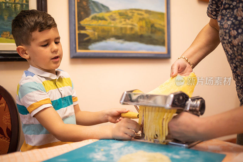 一个可爱的男孩和他的奶奶用意大利面机做意大利面