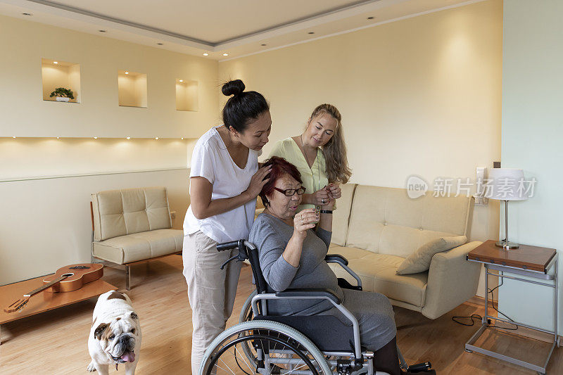 年轻女性理疗师正在为一位在家坐轮椅的老年妇女提供治疗。