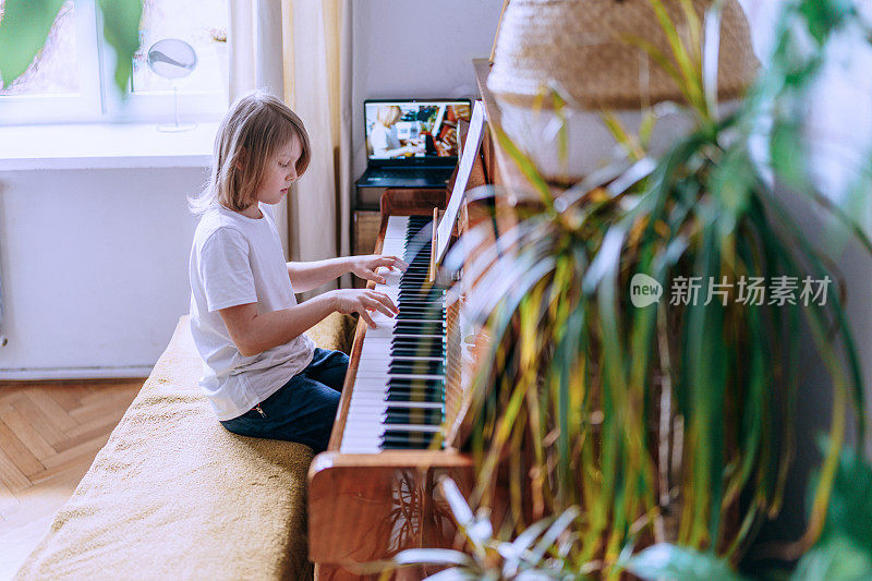 小男孩在上在线钢琴课。家庭教育。
