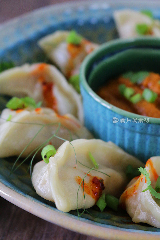 这是蒸过的馍馍(南亚饺子)，用白面粉和水面团填满鸡肉和什锦蔬菜，淋上辣椒油，放在盘子里，周围是用橙子辣酱做的小模子