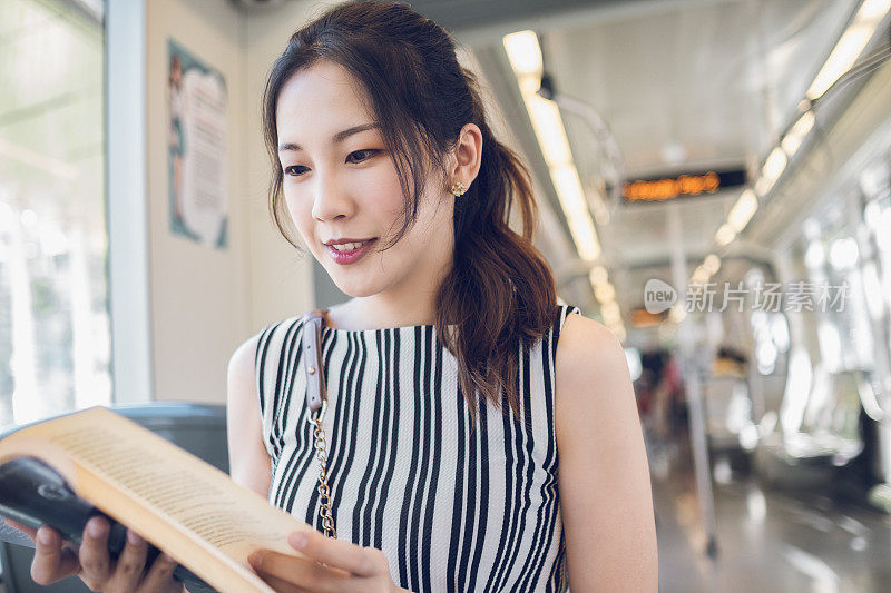 一个亚洲女人在地铁里看书