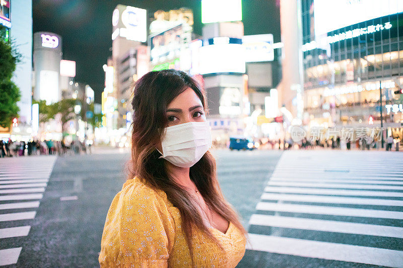 东京涉谷十字路口，一名年轻女子晚上戴着面具的肖像