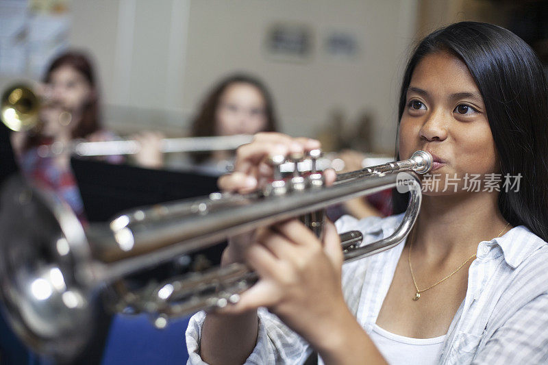 十几岁的亚裔菲律宾女孩在音乐课上吹小号