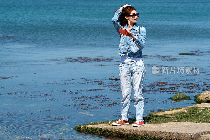一名游客在海边用智能手机自拍