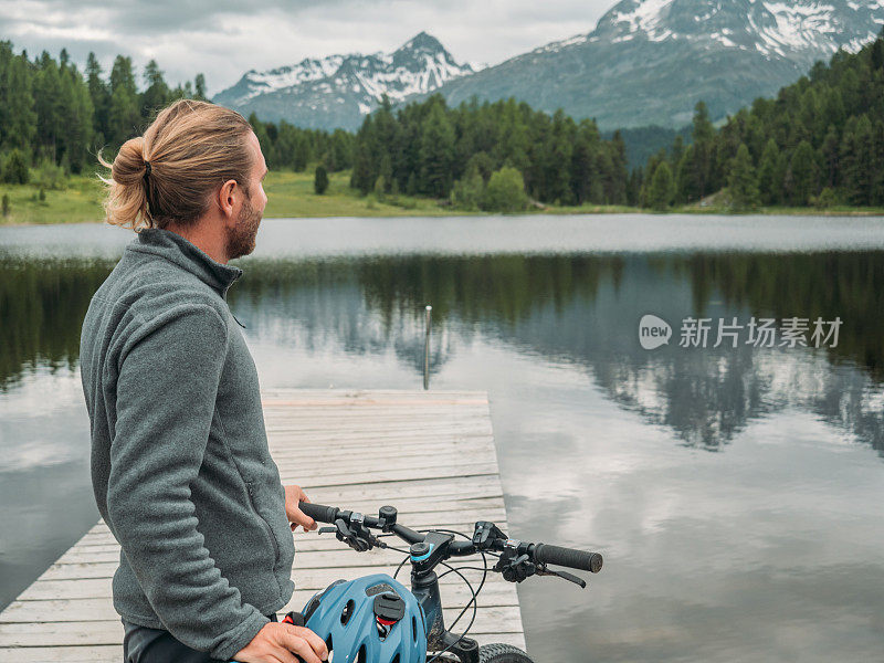 骑山地车的人在湖边看美丽的山景