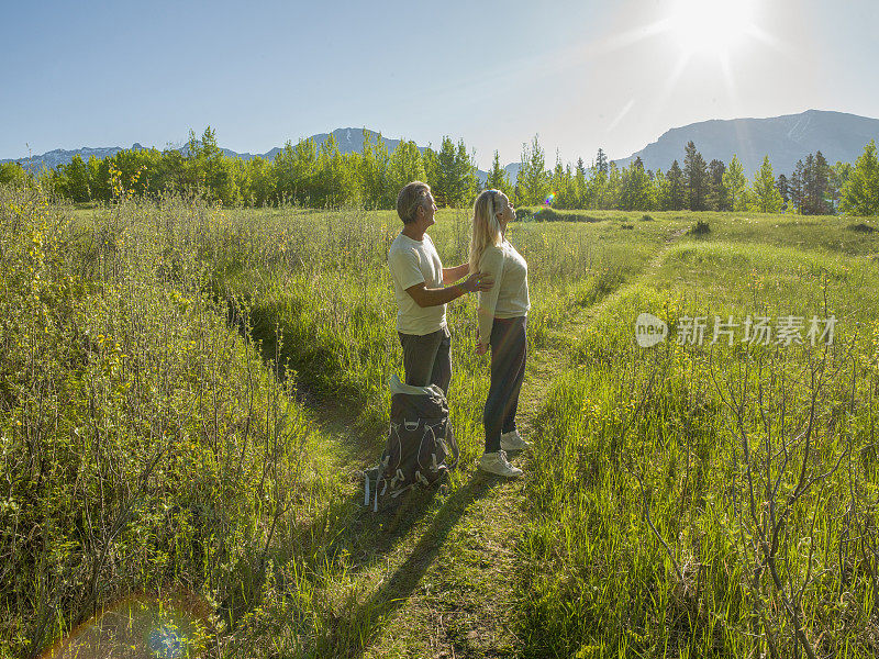 徒步旅行的夫妇沿着小路穿过绿色的山地草地