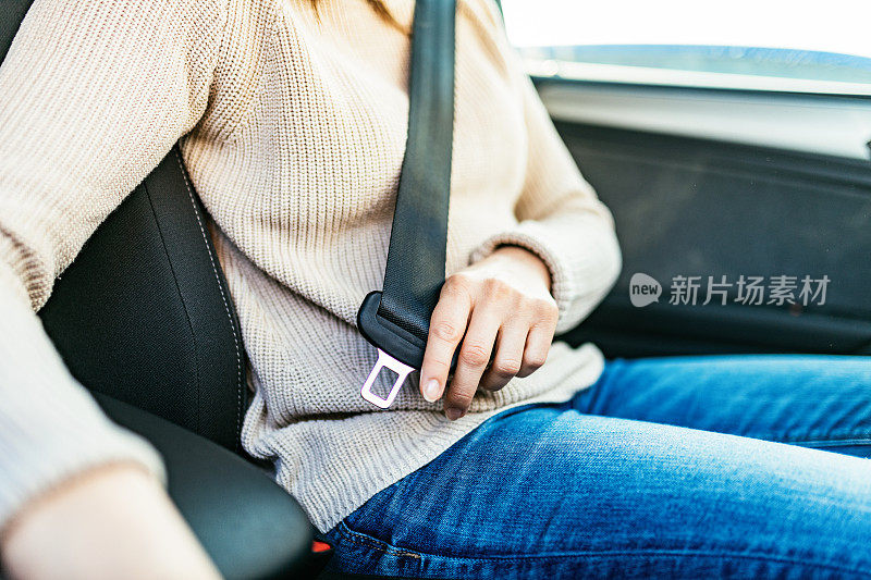 中年妇女在车里系上安全带，特写照片