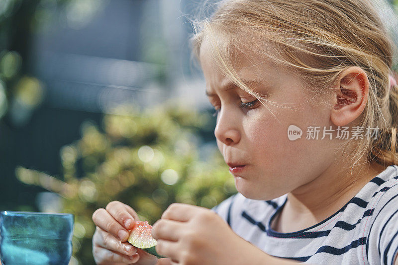 小孩子在外面的花园里吃新鲜的西瓜