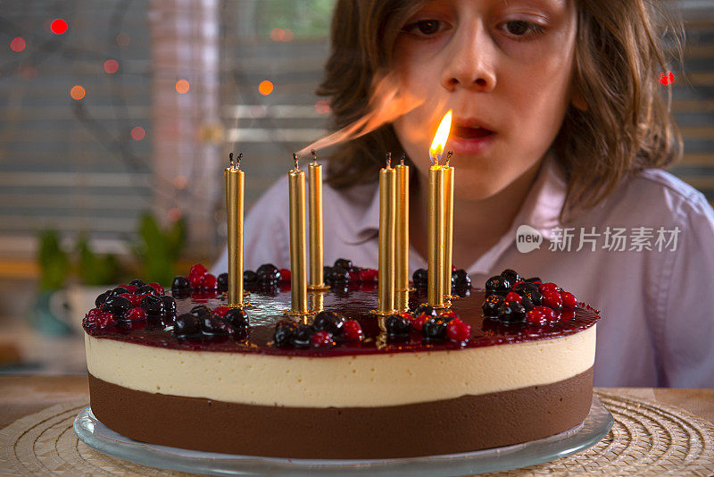 一个男孩吹灭生日蛋糕上的蜡烛。