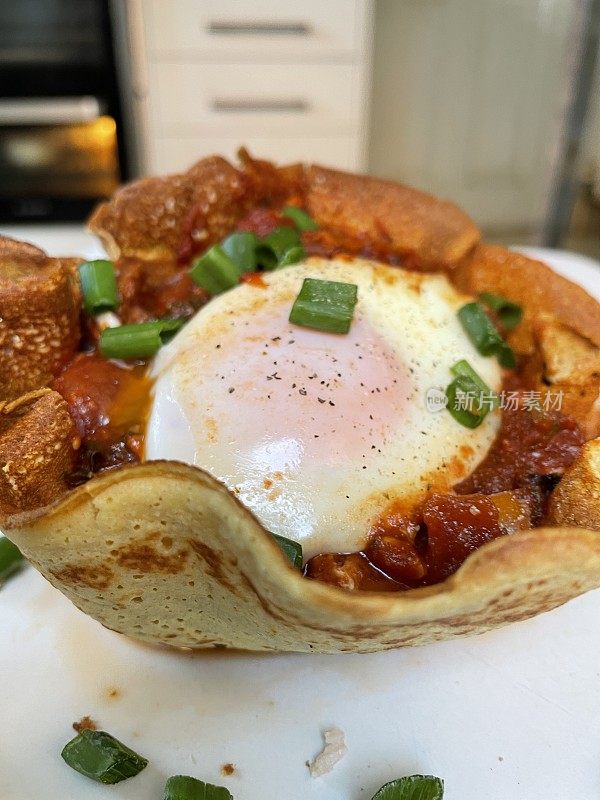 地中海健康早餐shakshouka由煎饼和鸡蛋做成的碗，鸡蛋是用西红柿、辣椒、洋葱、橄榄油和大蒜调味的