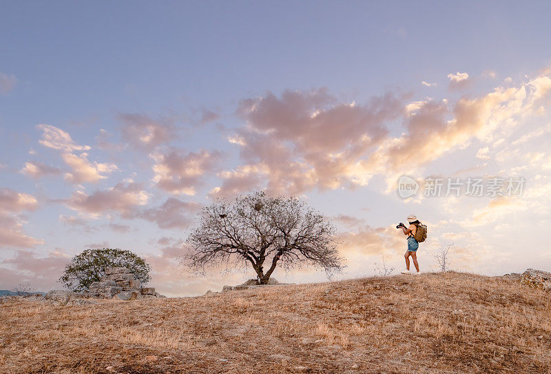 背包客摄影师女孩正在Pamukkale的Lycus上老底嘉古城遗址上拍摄孤独的树