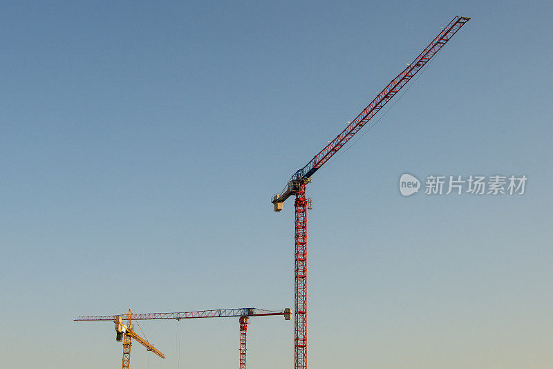 大型建筑起重机在一个大型工业建筑工地，夕阳的背景