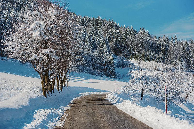 穿越白雪覆盖的风景的冬季道路