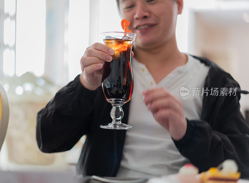 一个亚洲人拿起一杯加冰的苏打水