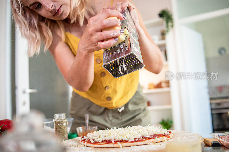 一位年轻女子正在家里准备披萨。网上食谱和食物准备。