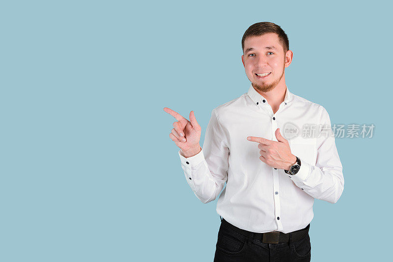 一个25-29岁，穿着白衬衫，留着胡子的男人站在蓝色的背景——copyspace上，双手做着食指的手势