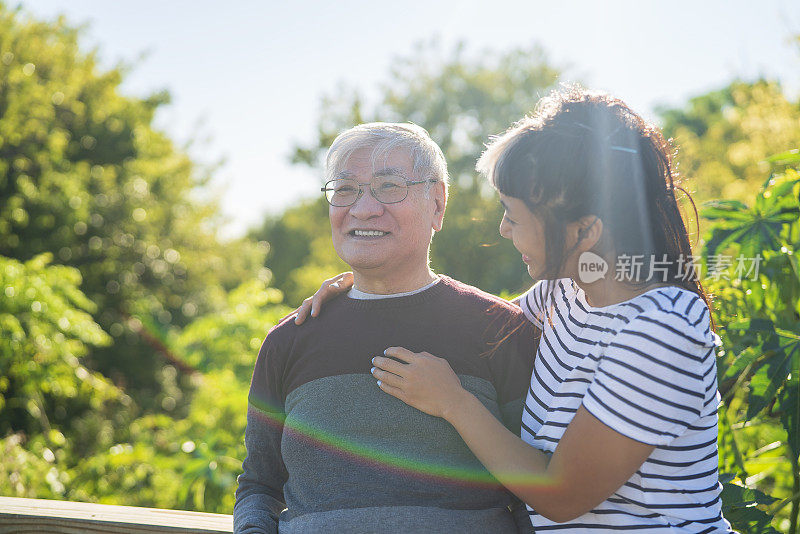 亚裔美国女人拥抱父亲，在户外有说有笑