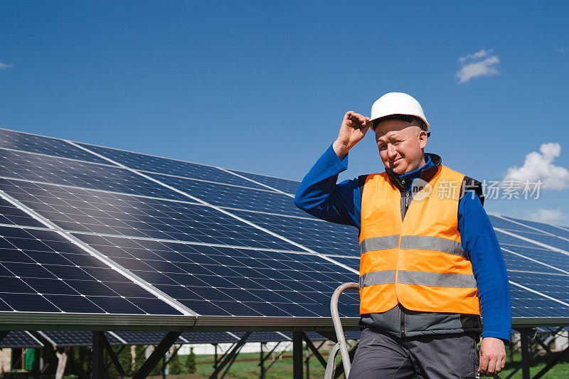一个工程师站在一个大的太阳能电池板旁的低角中景拍摄