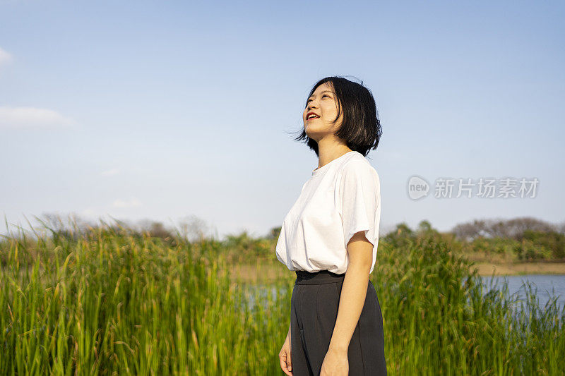 一位亚洲妇女在美丽的湖边眺望远方