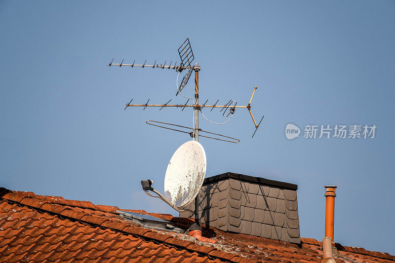 红色屋顶上的卫星天线和旧电视天线