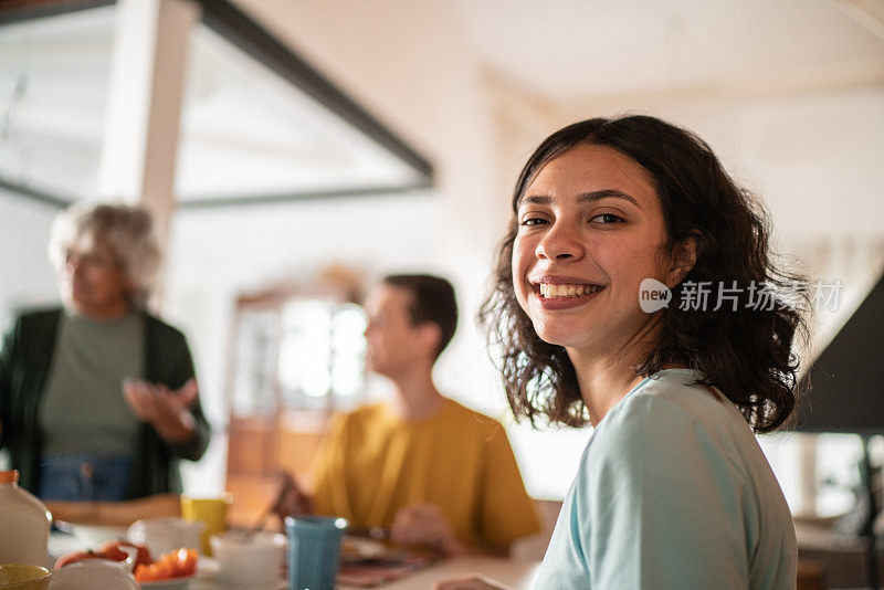 一个十几岁的女孩和家人在家里吃早餐的肖像