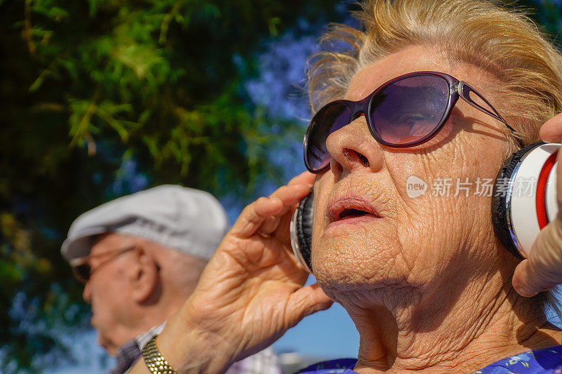 一对老夫妇在公园里戴着耳机听音乐。活跃的晚年。职业治疗