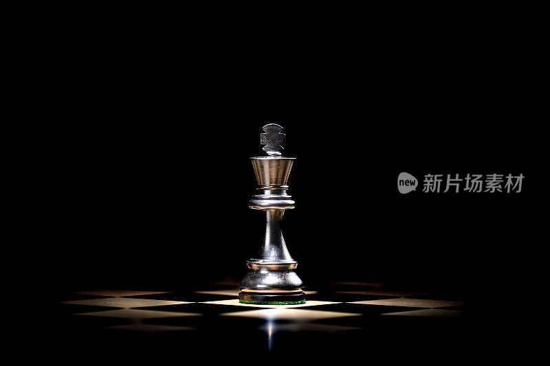 被聚光灯照亮的棋盘上光滑的棋子