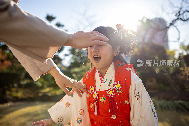 小女孩穿着和服与母亲在日本花园玩耍
