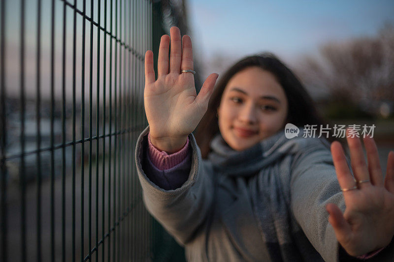 年轻的黑发女孩的肖像。
年轻女孩在看镜头时举手。