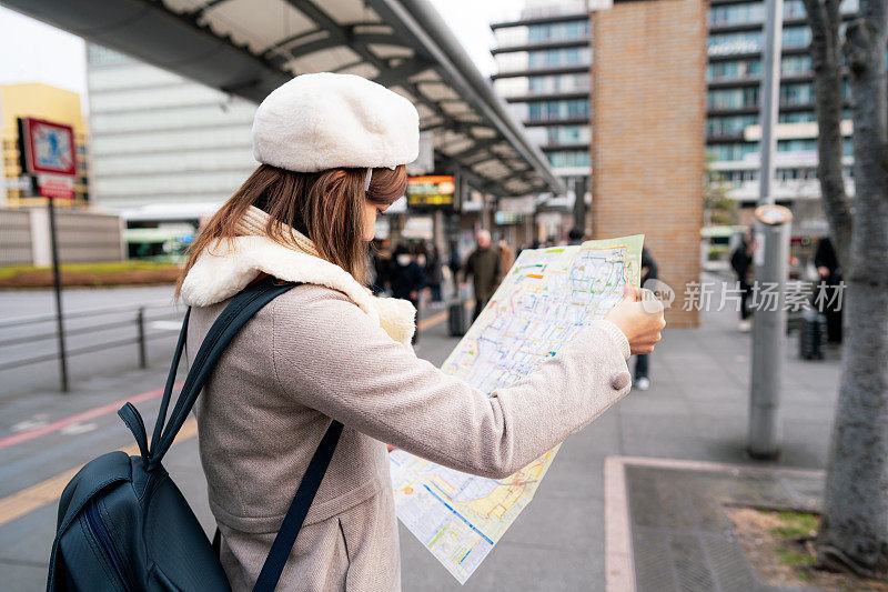 美女游客在日本一日游的巴士站看着当地的巴士地图