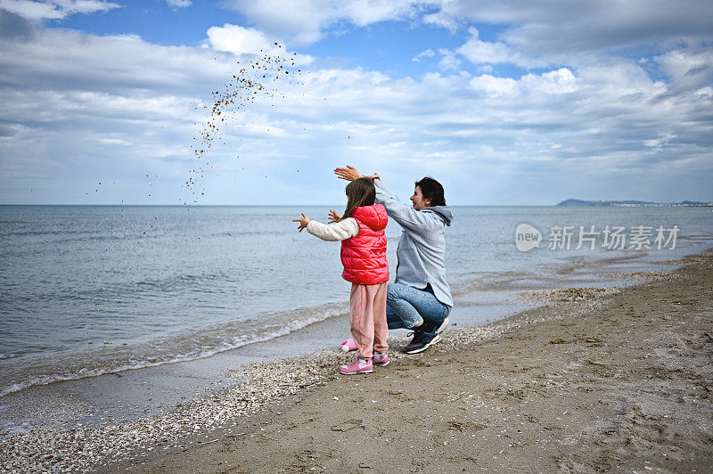 坦率的母亲和女儿在海滩上扔石头。