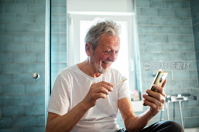 老人在浴室边刷牙边用智能手机