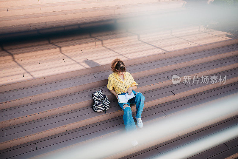 女学生下课后坐在城市外面的台阶上看书