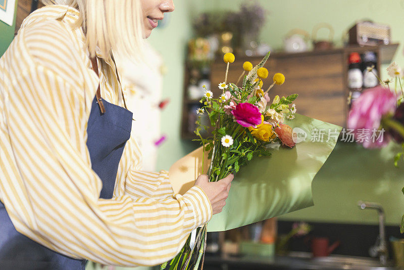 一位不知名的女花商正在准备一束花。经营小生意的日常工作