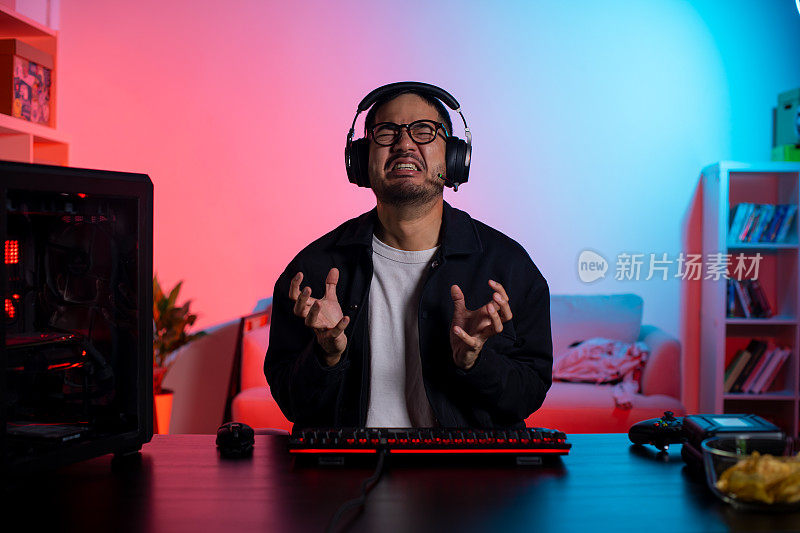 一名愤怒的亚洲年轻人正在玩电子游戏，输了游戏后他感到很沮丧