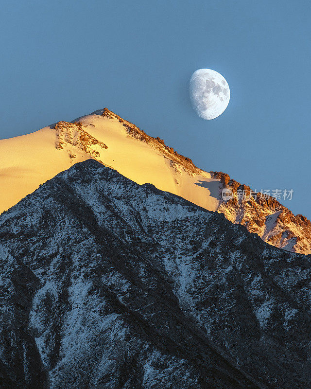 在哈萨克斯坦大阿拉木图峡谷的苏联峰和斯卡利斯峰，天山的阿拉托山脉，几乎满月和日落的山地景观
