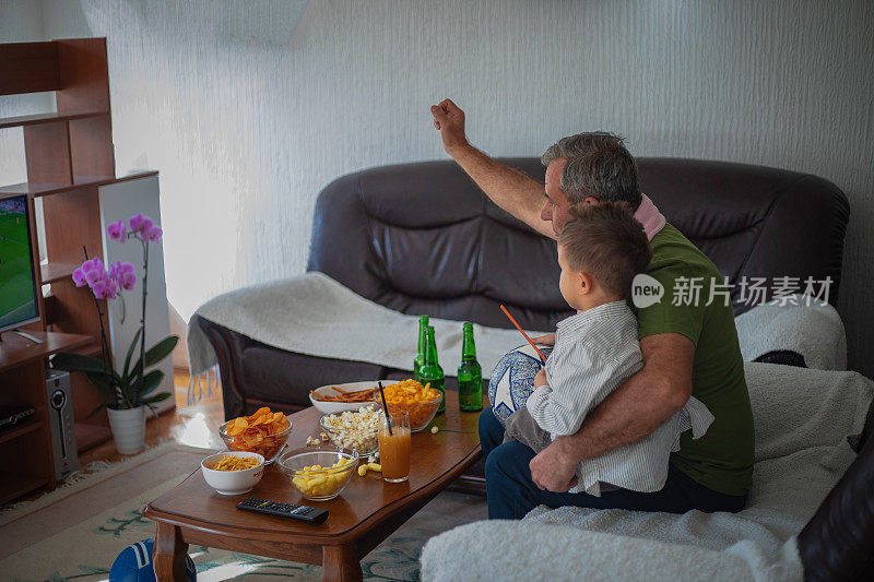 球迷们正在看电视，爷爷和孙子