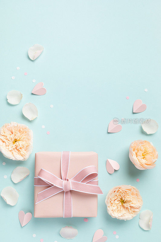 可爱的生日贺卡，女人或母亲节。粉红色的心，玫瑰花和礼盒上的蓝色粉彩桌面视图。