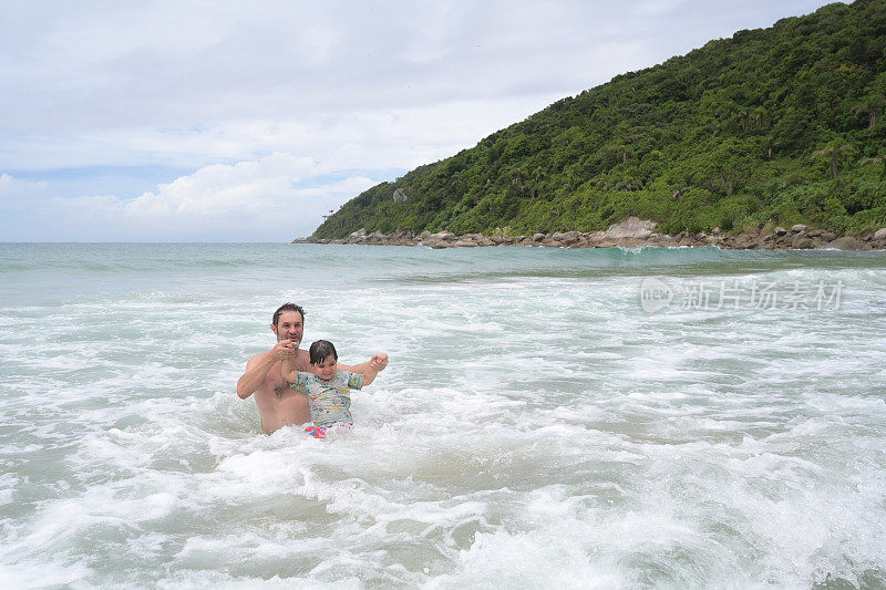 父子俩在海浪中嬉戏