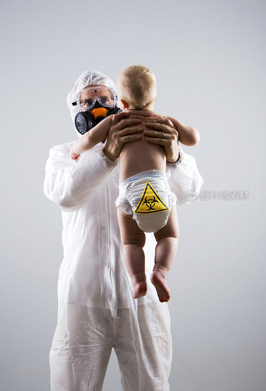 穿着防护服的男人抱着婴儿，小心尿布