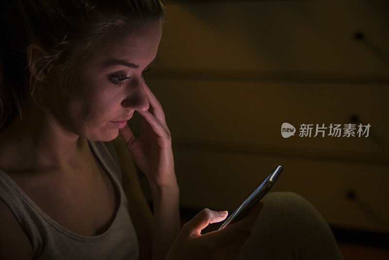 一位年轻的亚洲女性从她的智能手机上得到了坏消息