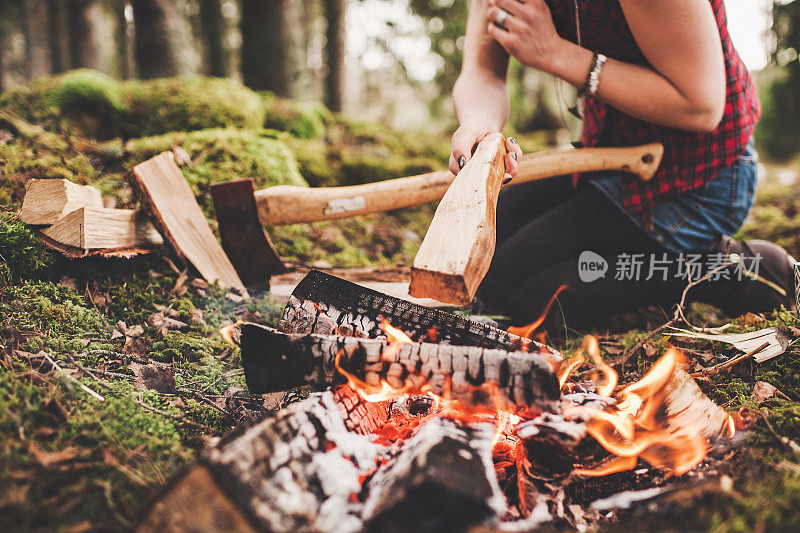 在森林里篝火旁砍柴的女人