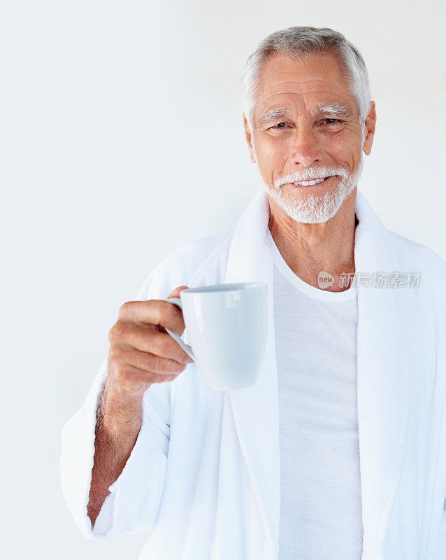 一个快乐英俊的老人拿着一杯咖啡微笑着