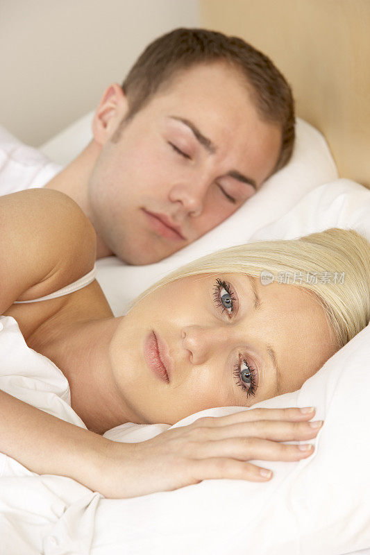 醒着的年轻女人在熟睡的男人旁边