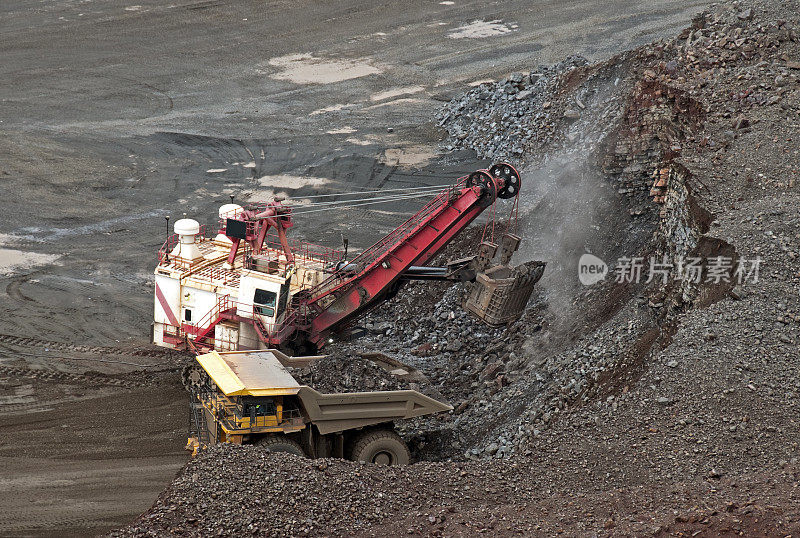 在矿山将铁矿石装载到卡车上的起重机斗