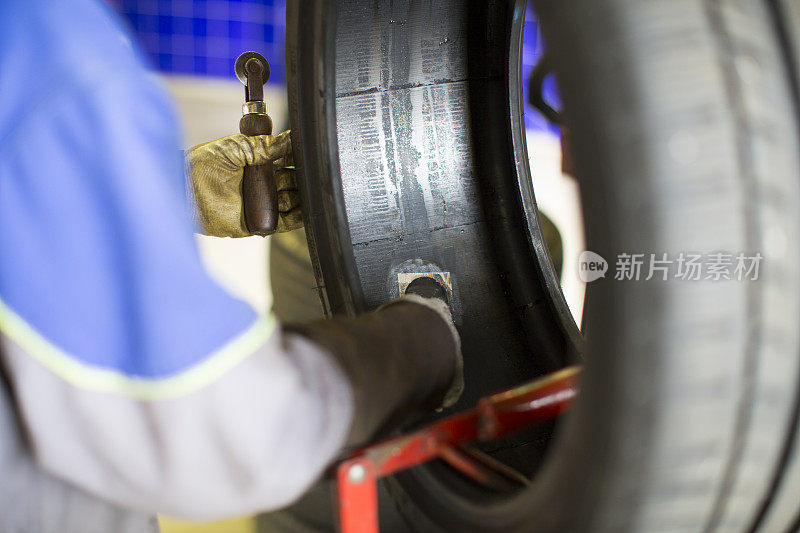 在一个汽车修理厂…汽车修理工正在修补漏气的轮胎