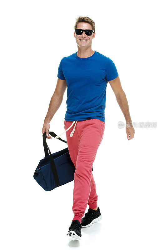 微笑随意的男人拿着行李袋走路